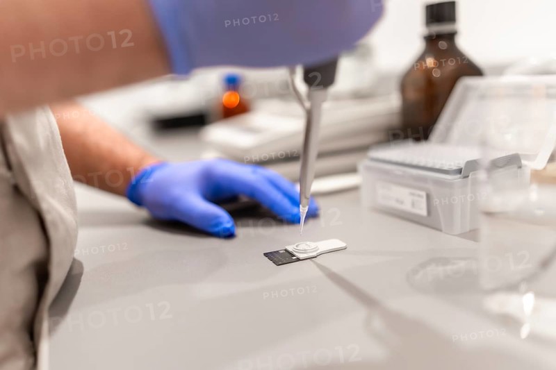 Side view close-up of an unrecognizable doctor using pipette to test samples in a pharmacy laboratory