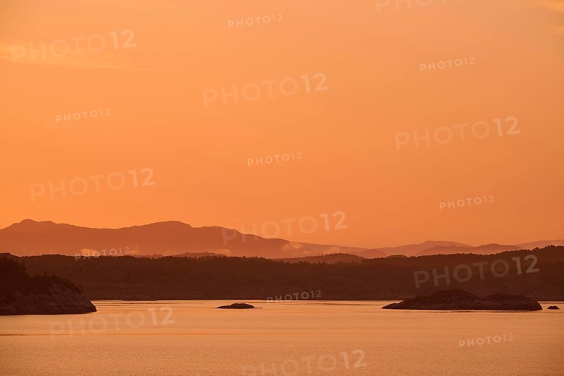 Atmospheric landscape scene at sunrise with pastel-coloured sky, calm sea and silhouetted islands in the twilight, autumn, Bergen, North Sea, Norway