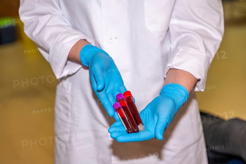 Unrecognizable doctor with blue gloves collecting samples of blood and holding them in a donation center