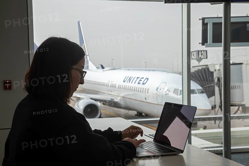 Denver, Colorado, A traveler works on a laptop while waiting for her flight at Denver International Airport (DEN)