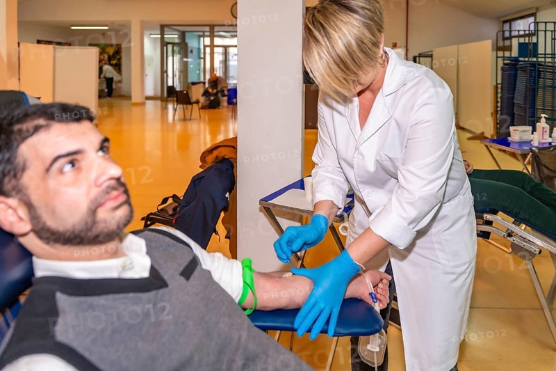 Focus on a female doctor preparing a patient for blood donation while he is sitting patiently on a chair