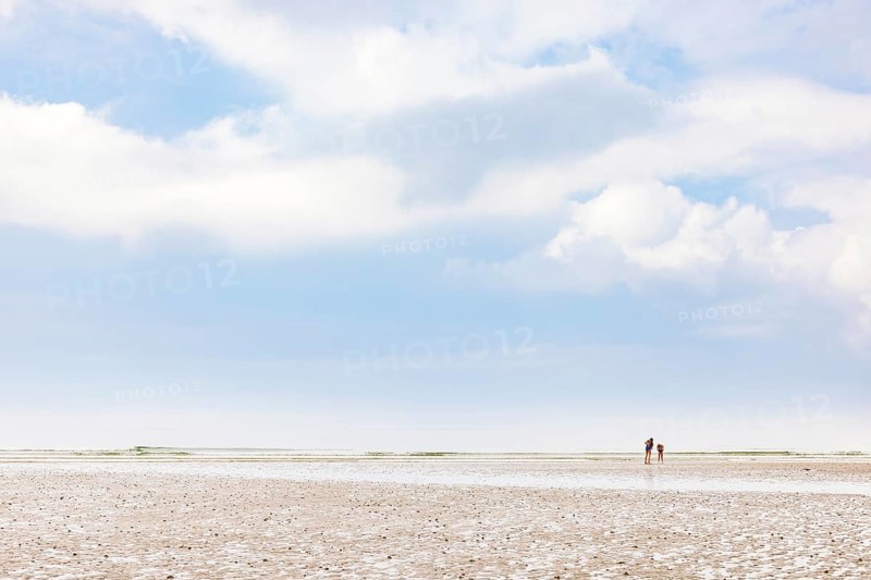 Children in swimsuits on a sand beach in low tide and a view to the horizon a summer day, Crozon peninsula, Bretagne, France