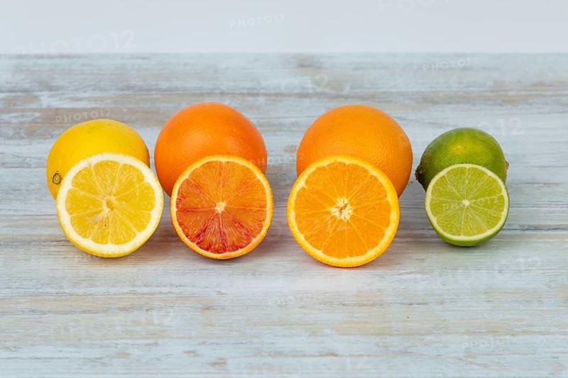 Rows of whole and halved oranges, lemons and limes on a table