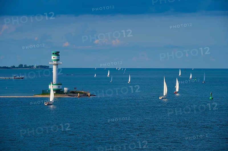 Several sailing boats and ships on calm blue sea under a cloudy sky with a lighthouse in the background, Lighthouse Friedrichsort, Kiel, Schleswig-Holstein, North Sea, Germany