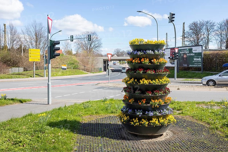 Cascading plant pot with spring planting on Dresdner Straße, corner of Am Güterbahnhof, railway bridge in the background, Coswig, Saxony, Germany