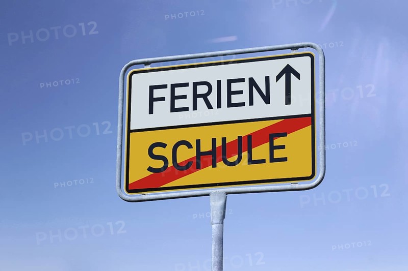 Symbolic image summer holidays: German town exit sign with the words Schule/Ferien in front of a blue sky (Composing)