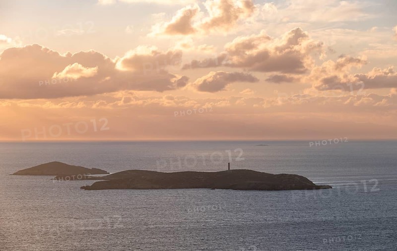 Nisos Gaidaros island with lighthouse in the sea at sunrise with dramatic clouds, Ermoupoli, Syros, Cyclades, Greece
