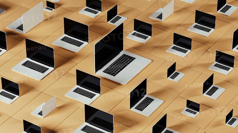 Laptops arranged in a unique pattern create an engaging technological backdrop with geometric shapes, showcasing a contemporary digital aesthetic