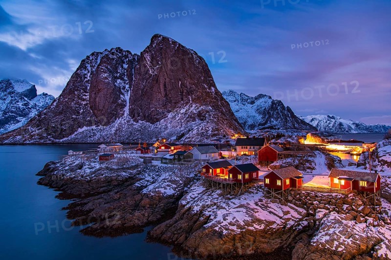 Fishermen's Village in front of snowy mountain range at the coastline in winter, Lofoten, Norway