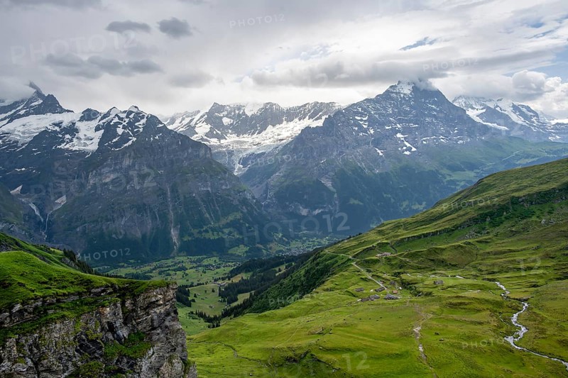 View of mountain landscape with green meadows and alpine huts Bachlager, Grindelwald First, snow-capped Eiger mountain peak, Grindelwald, Bernese Alps, Bernese Oberland, Switzerland
