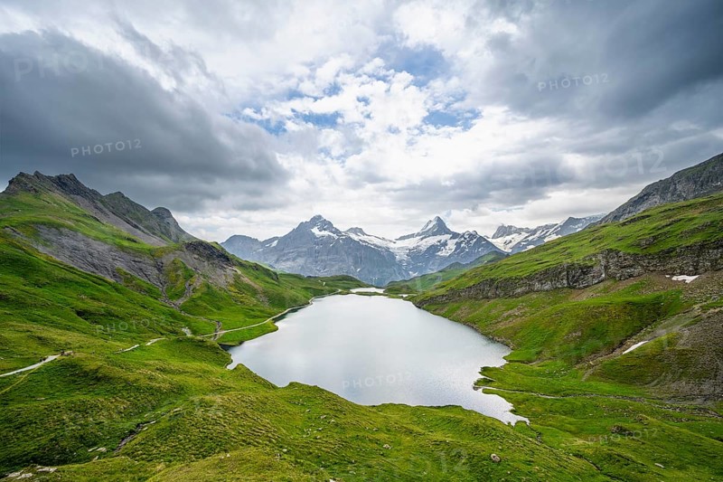 View of mountain landscape with Bachalpsee mountain lake, Finsteraarhorn peaks and Schreckhorn with Upper Eismeer glacier, dramatic cloudy sky, Bernese Alps, Bernese Oberland, Switzerland