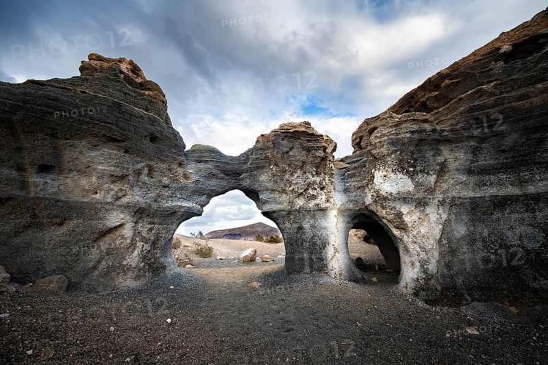 Eroded rock formations, volcanic landscape with dramatic cloudy skies, Ciudad Estratificada or Los Roferos, Antigua Rofera de Teseguite, Lanzarote, Canary Islands, Spain