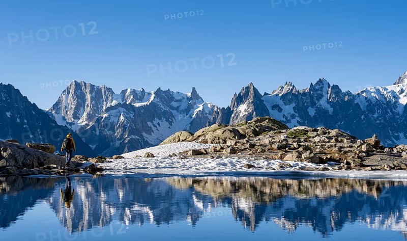 Young man hiking along a mountain lake, mountain landscape in morning light, reflection in Lac Blanc, mountain peak, Aiguille Verte, Grandes Jorasses, Aiguille du Moine, Mont Blanc, Mont Blanc Massif, Chamonix-Mont-Blanc, Haute-Savoie, France