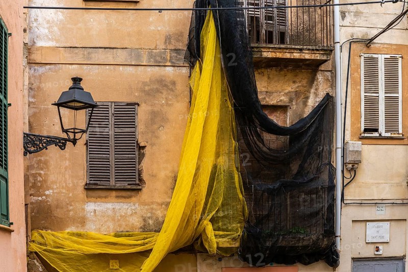Yellow and black safety nets at the construction site of a house in Carrer de Sant Pere, Palma de Majorca, Spain