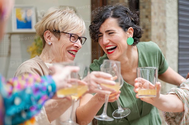 Two coworkers joyfully toast drinks at a lively gathering. Their expressions are full of happiness, capturing a moment of friendship and celebration