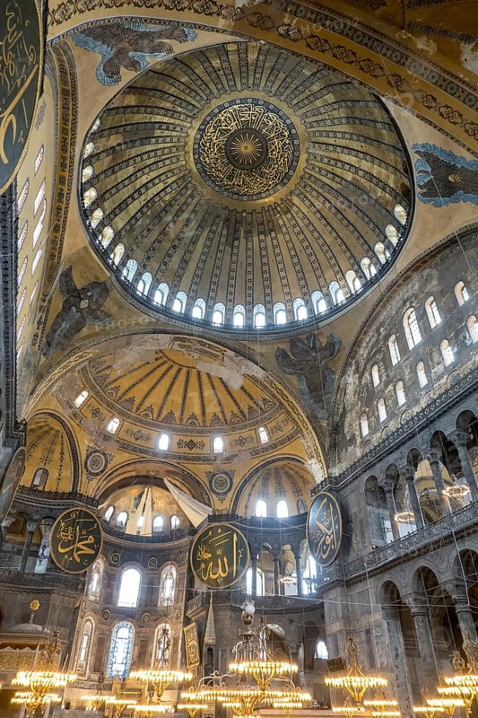 This photo captures the grandeur of Hagia Sophia's mosque interior in Istanbul, highlighting its enormous dome, ornate mosaics, and Islamic calligraphy