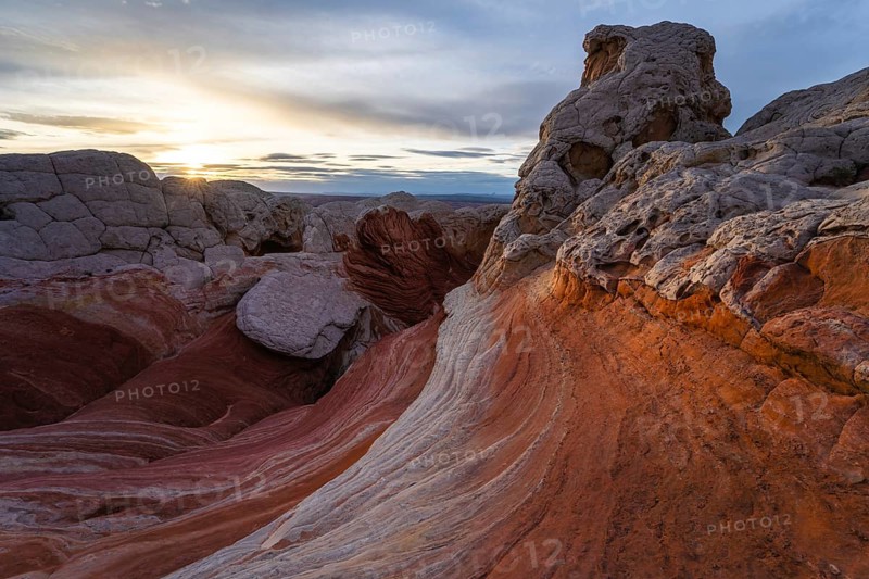 Enchanting view of a vibrant sunset casting warm hues over the twisted rock formations and colorful striations at White Pocket in Arizona, USA, showcasing nature's artistry