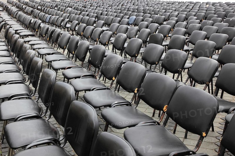 Chairs covered with gray plastic stand in rows in a function room, empty, vacant, seating