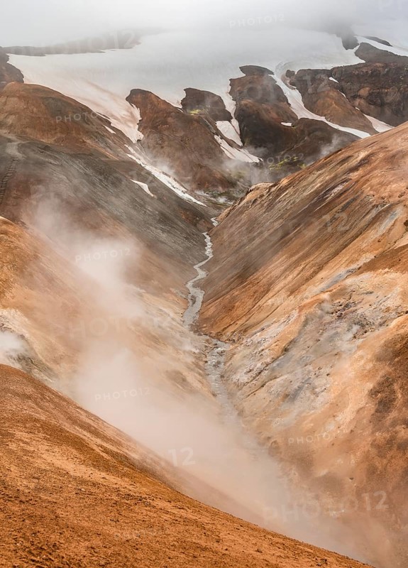 Steaming stream between colourful rhyolite mountains and snowfields, Hveradalir geothermal area, Kerlingarfjöll, Icelandic Highlands, Iceland