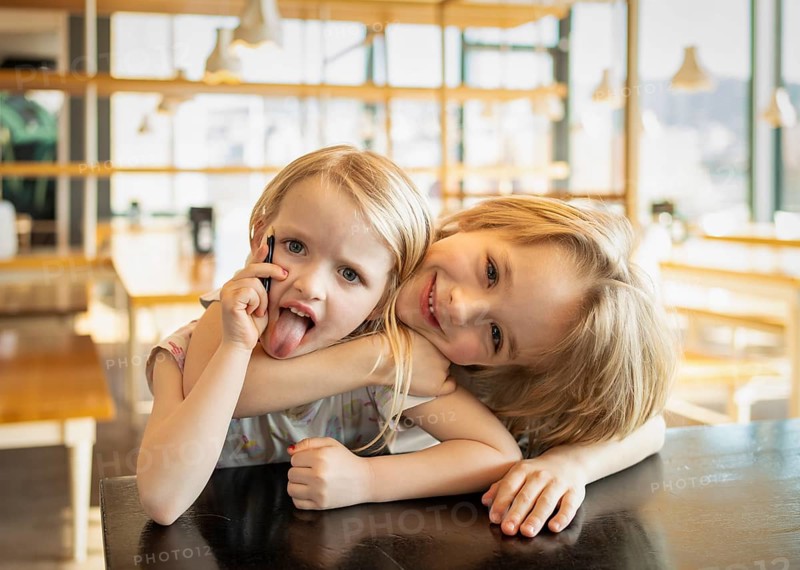 Interior view, siblings, girl, 4 years, blonde, boy, 7 years, blonde, silly, grimaces, sticks out tongue, hug, sibling love, Stuttgart, Baden-Württemberg, Germany