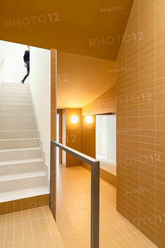Contemporary stairway featuring vibrant yellow tiles, walls and ceiling for an eye-catching design. Highlighting sustainable architectural elements aimed at reducing emissions
