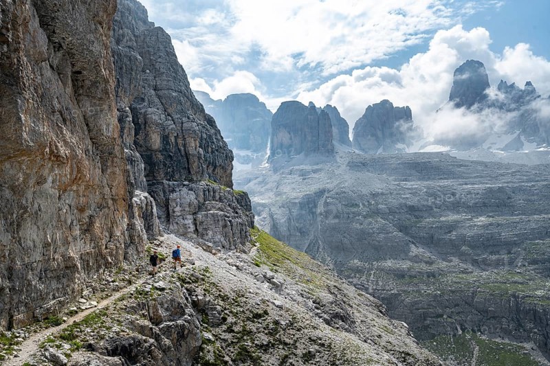 Two mountaineers on a hiking trail in front of a picturesque mountain landscape with rocky peaks, Via Ferrata SOSAT via ferrata, summit of Cima Tosa in the back, Brenta Mountains, Trentino, Italy