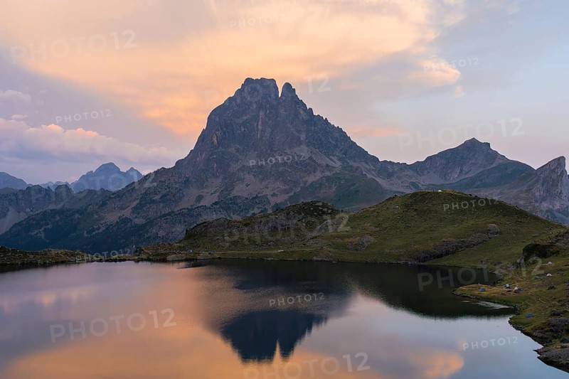 Landscape of Midi d'Ossau, in the French Pyrenees, The mountain and its reflection create a tranquil scene combining natural beauty and a peaceful atmosphere, while campers are in the background