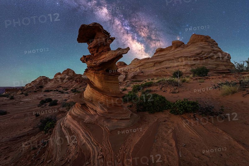 A stunning desert landscape features unique rock formations beneath a vivid Milky Way, showcasing the beauty of nature night sky in Coyote Buttes, Arizona. Captivating hues paint a serene scene