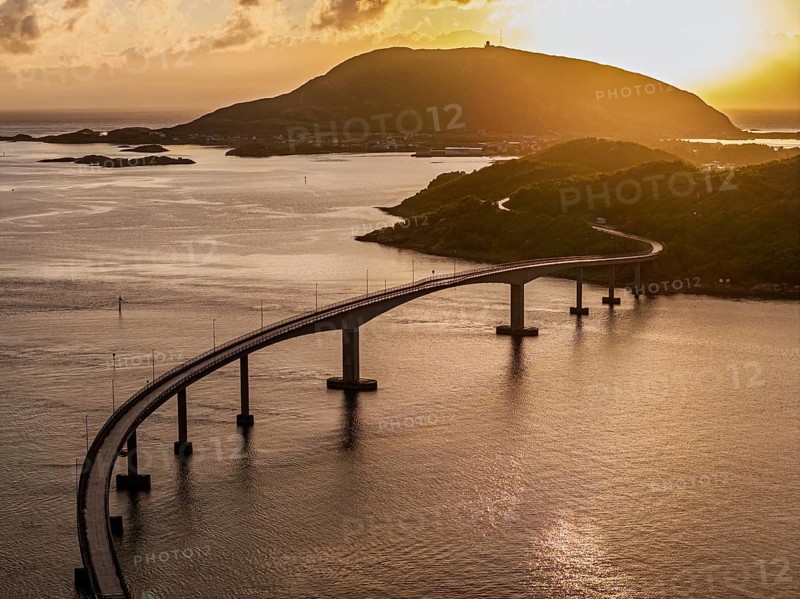 Sommaroy Bridge connecting Kvaloya Island to Sommaroy Island, warm light at sunset, aerial view, Norway