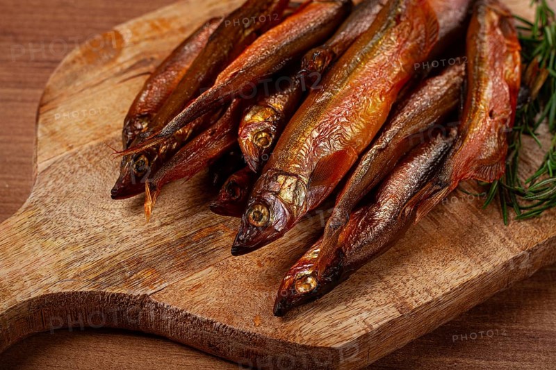 Cold smoked capelin, on a wooden chopping board, no people