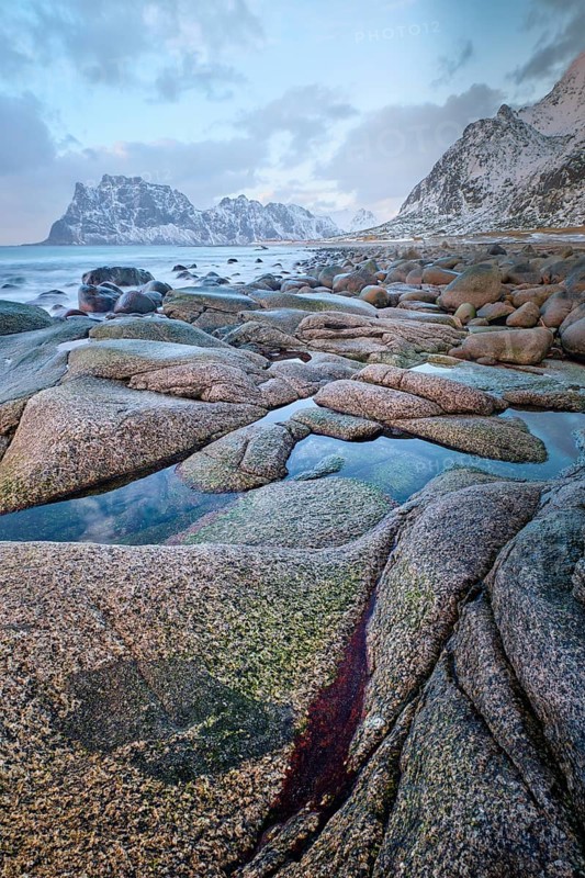 Rocks on beach of fjord of Norwegian sea in winter on sunset. Utakliev beach, Lofoten islands, Norway
