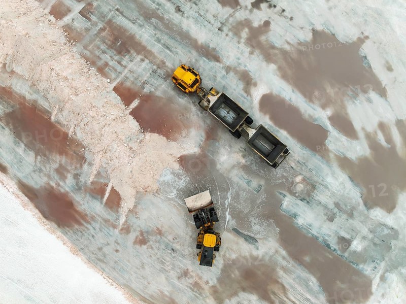 Excavator and lorry at a harvesting pan of the Walvis Bay Salt works. Aerial view. Drone shot. Walvis Bay, Namibia