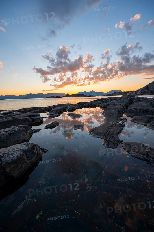 Clouds reflected in a small pond on a rocky coast, coastal landscape at sunset, Henningsvær, Lofoten, Nordland, Norway
