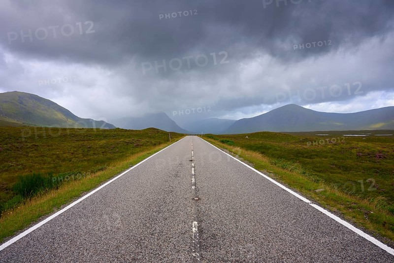 A long, straight road leads through a vast landscape of low-hanging clouds and mountains, Rannoch Moor, Bridge of Orchy, Scotland, United Kingdom, Great Britain