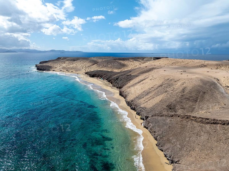 Coast with Playa Caleta del Congrio beach and blue sea, arid landscape of Los Ajaches Natural Park, aerial view, Lanzarote, Canary Islands, Spain