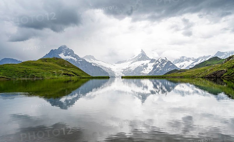 Mittelhorn and Schreckhorn peaks with Upper Grindelwald glacier are reflected in the Bachalpsee mountain lake, dramatic cloudy sky, Bernese Alps, Bernese Oberland, Switzerland