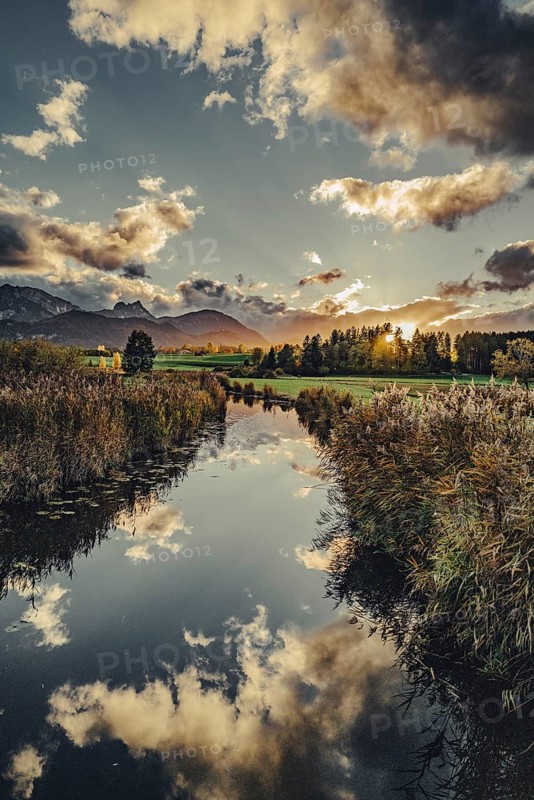 Lake Hopfensee in the Allgäu in autumn with warm sunset light against a picturesque Alpine backdrop, Bavaria, Germany