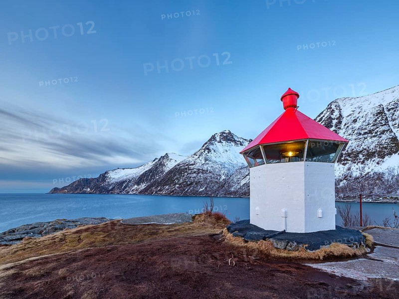 Small lighthouse at the end of Husøy island with a view across the fjord to the sea, Senja island, Troms, Norway