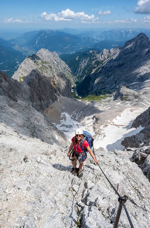 Mountaineer with helmet in a secured via ferrata, Zugspitze via ferrata, ascent to the Zugspitze, view of mountain basin with snow field of the Höllentalferner and Höllental, Wetterstein range, Wetterstein range, Bavaria, Germany