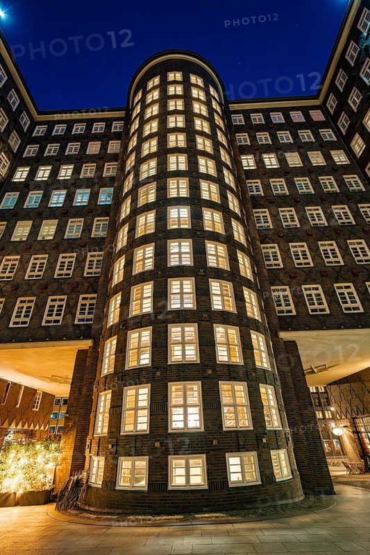 Illuminated brick facade of a tall office building with many windows, taken at night, Hamburg, Germany