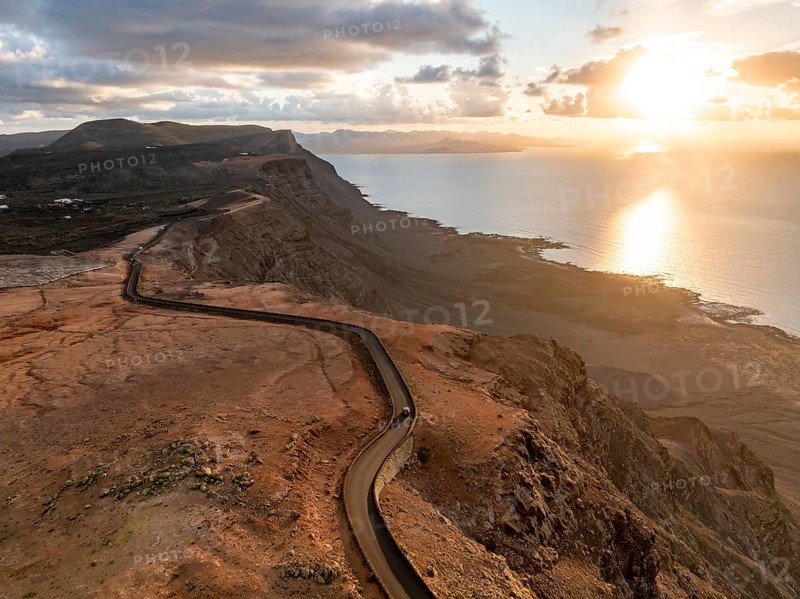 Road on cliffs in evening light, steep cliffs on the coast near Mirador del Porrito, aerial view, at sunset, Lanzarote, Canary Islands, Spain