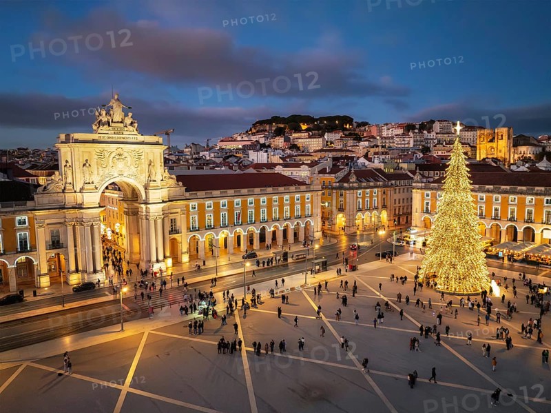 Praca do Comercio glows with festive Christmas lights and a tall tree during a winter evening in Lisbon's charming twilight