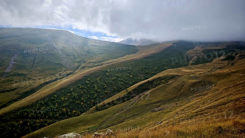 Misty mountain landscape with rolling hills and cloudy sky, Stepantsminda, Caucasus, Georgia