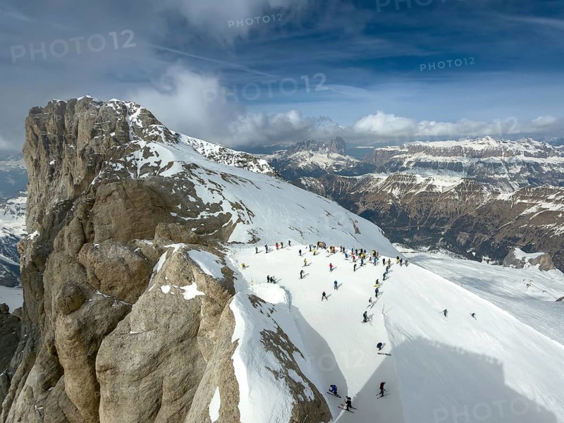View of the snow-covered Marmolta (3343 m) with skiers in the foreground and clouds in the background, Trentino, Dolomites, Italy