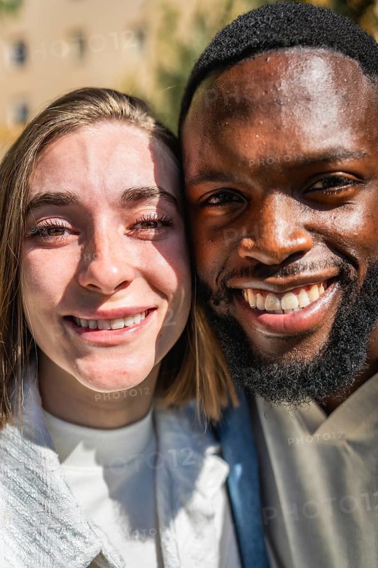 Vertical close-up portrait of a smiling multiracial young couple outdoors