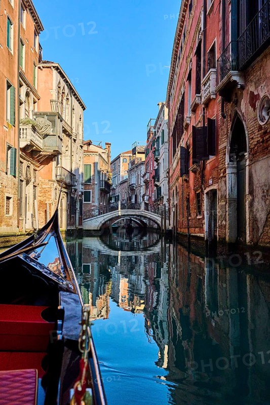 View from a gondola on a waterway in Venice going through the houses on a quiet and sunny morning in winter, Italy