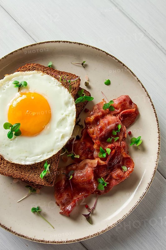 Breakfast, fried egg with bacon, micro-green, on a light background, no people, selective focus