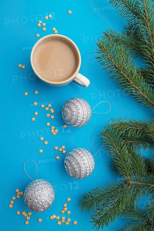 Christmas or New Year composition. Decorations, silver balls, fir and spruce branches, cup of coffee, on a blue paper background. Top view, close up, flat lay