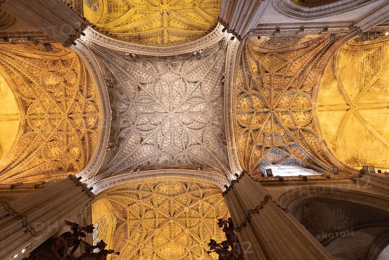 Majestic Gothic vault with detailed decorations and warm lighting, Seville, Andalusia, Spain