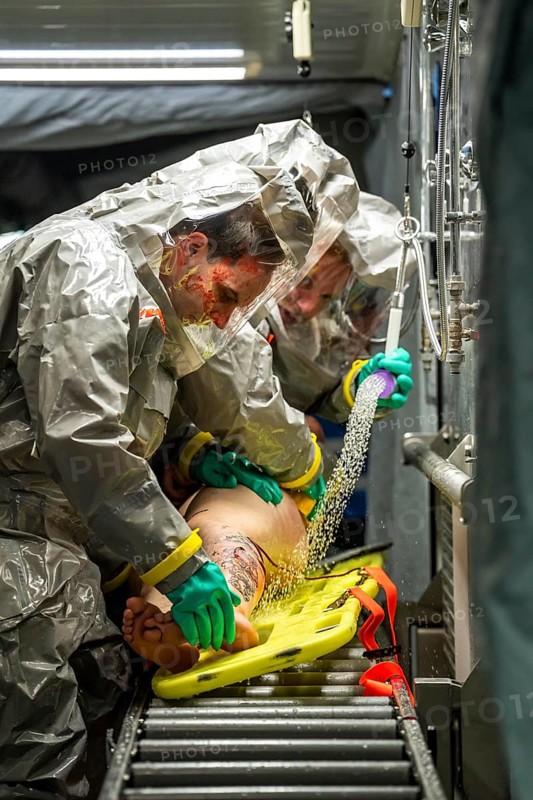 Decontamination of injured persons after an assumed accident involving hazardous substances, fire brigade and aid organisations practise setting up and operating a decontamination station, injured persons are sighted and then washed in a special shower tent to remove possible hazardous substances and chemicals in order to avoid further injuries, the emergency services wear special, ventilated protective suits, large-scale exercise by the Essen fire brigade